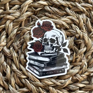 May include: A black and white illustration of a skull with red roses on top of a stack of books.