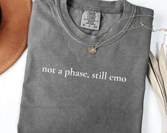 May include: Gray cotton t-shirt with the text "not a phase, still emo" printed in white.