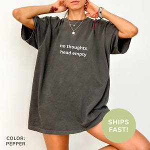 May include: An oversized t-shirt in a dark grey colour with the text "no thoughts head empty" printed in white on the front.