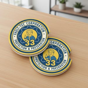 May include: Two round car coasters with a yellow and blue design. The coasters feature the text "VAULT-TEC CORPORATION" and "PROTECTION & PRESERVATION" around a cartoon character giving a thumbs up. The number "33" is also visible.