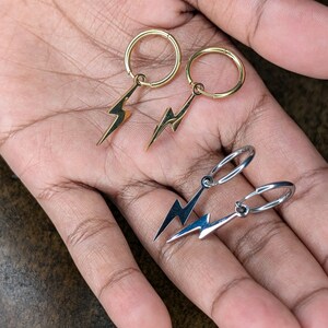 Pode incluir: Dois pares de brincos com pingentes de raio. Um par &eacute; dourado e o outro &eacute; prateado.