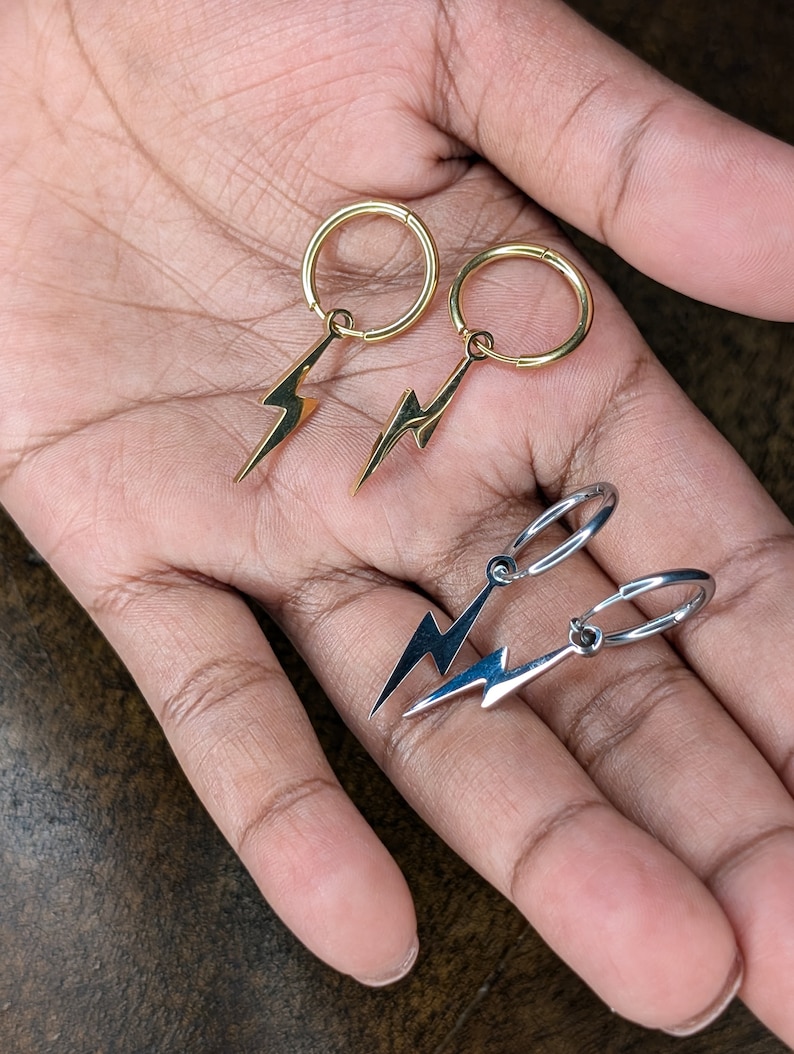 Pode incluir: Dois pares de brincos com pingentes de raio. Um par &eacute; dourado e o outro &eacute; prateado.