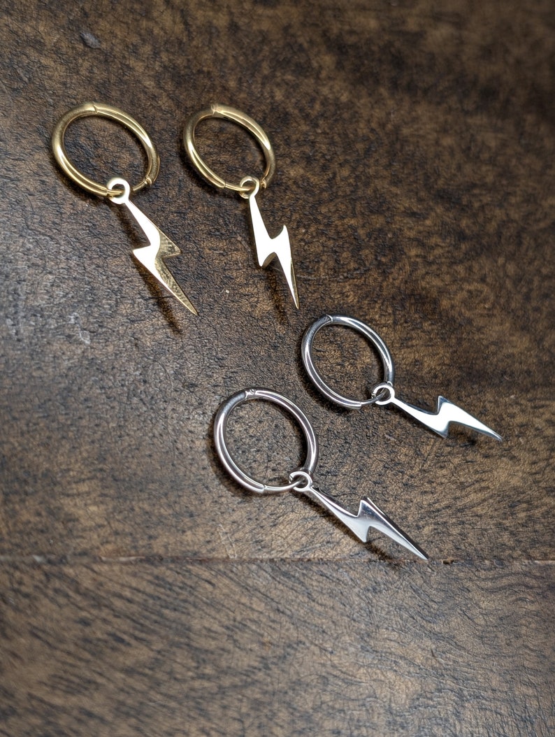 Pode incluir: Quatro pares de brincos com um charme de raio. Dois pares s&atilde;o dourados e dois pares s&atilde;o prateados.