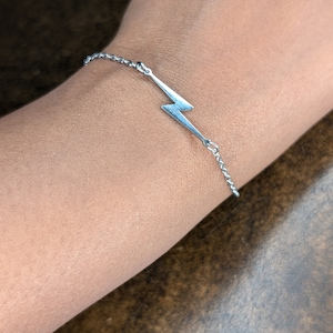 May include: A silver chain bracelet with a lightning bolt charm.