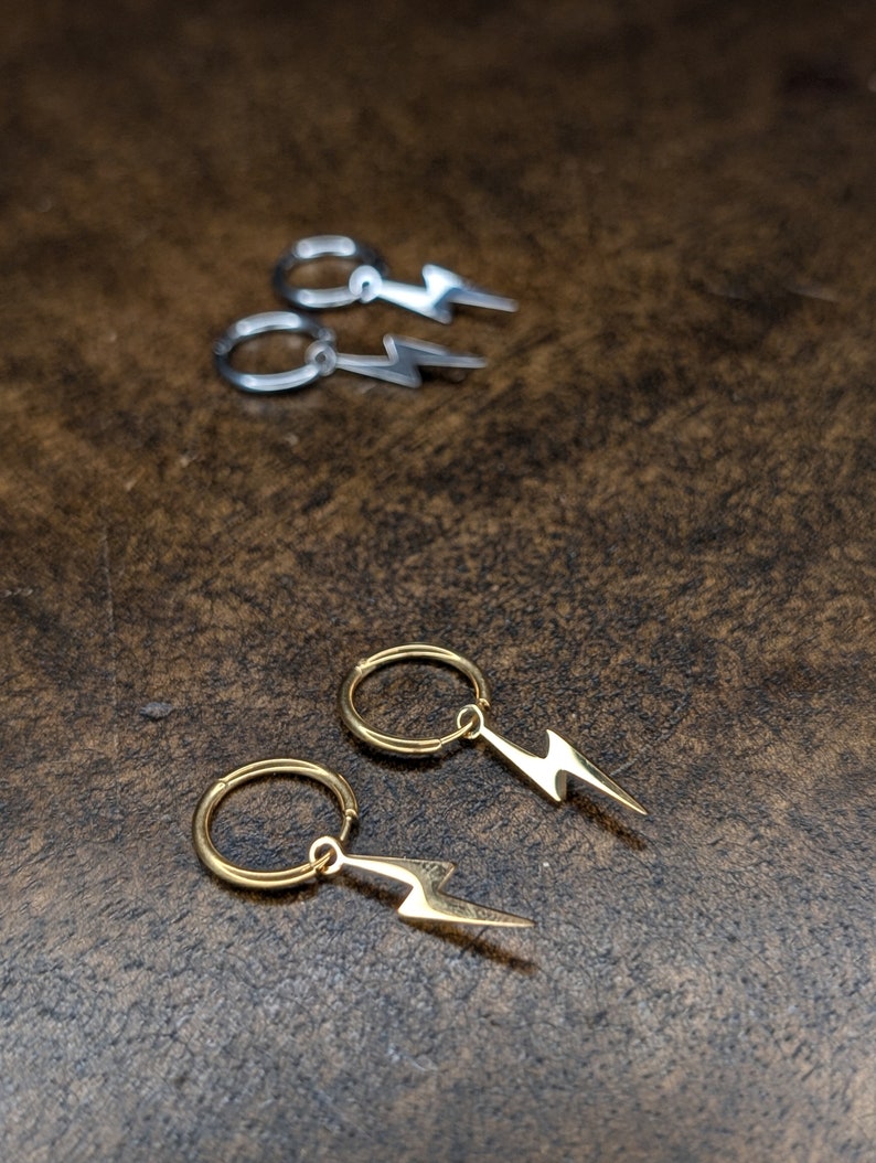 Pode incluir: Dois pares de brincos com um design de raio. Um par &eacute; dourado e o outro &eacute; prateado.