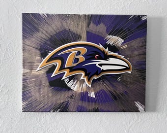 Könnte beinhalten: Leinwanddruck mit dem Logo der Baltimore Ravens. Das Logo, ein Rabenkopf mit dem Buchstaben "B", ist in Weiß, Gold und Lila gehalten. Der Hintergrund hat ein radiales Design in Lila-, Schwarz- und Grautönen.