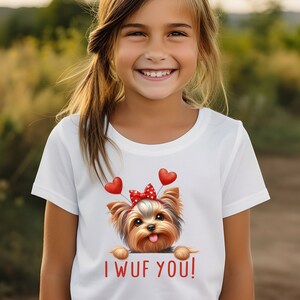 May include: White t-shirt with a cartoon Yorkshire Terrier wearing a red bow and red heart balloons. The text "I WUF YOU!" is printed below the dog.
