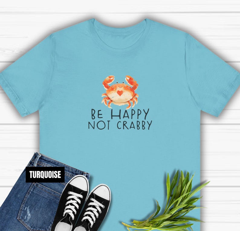 May include: A turquoise blue t-shirt with a cartoon crab and the text "Be Happy Not Crabby".