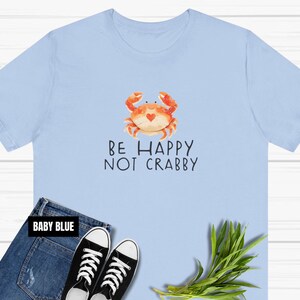 May include: A light blue t-shirt with a cartoon crab and the text "Be Happy Not Crabby".