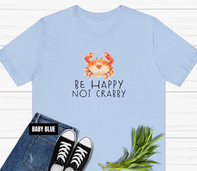 May include: A light blue t-shirt with a cartoon crab and the text "Be Happy Not Crabby".