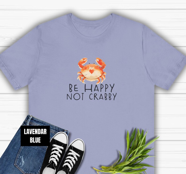 May include: Lavender blue t-shirt with a cartoon crab and the text "Be Happy Not Crabby".