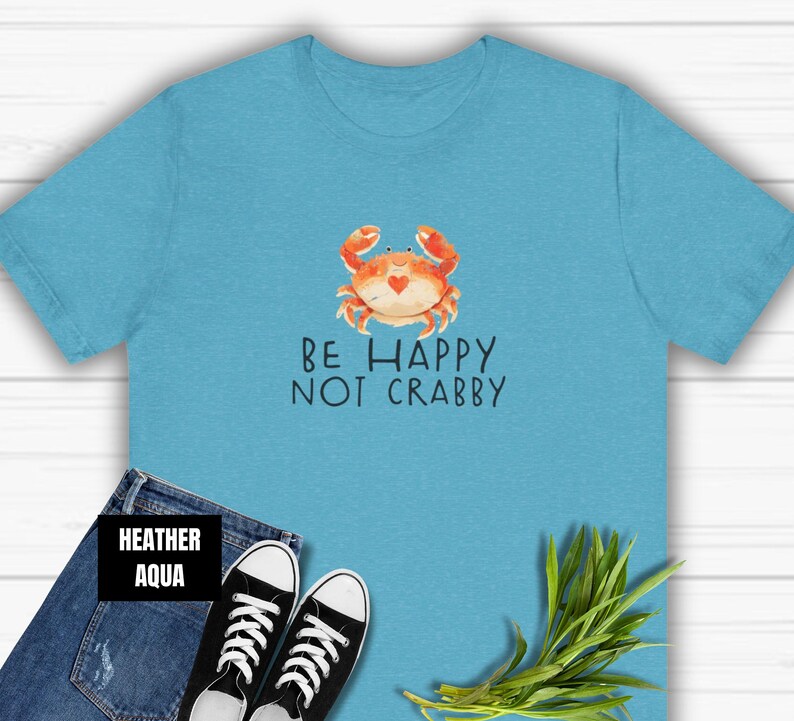 May include: A light blue t-shirt with a cartoon crab and the text "Be Happy Not Crabby".