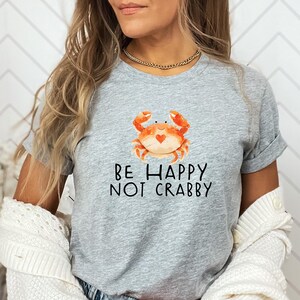 May include: Gray t-shirt with a cartoon crab and the text "Be Happy Not Crabby".