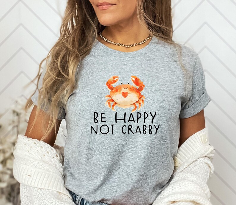May include: Gray t-shirt with a cartoon crab and the text "Be Happy Not Crabby".