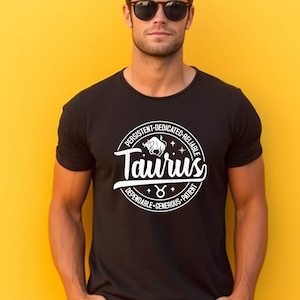 May include: Black t-shirt with a white circle graphic featuring the Taurus zodiac sign and the words "Taurus", "Persistent", "Dedicated", "Reliable", "Dependable", "Generous", and "Patient".