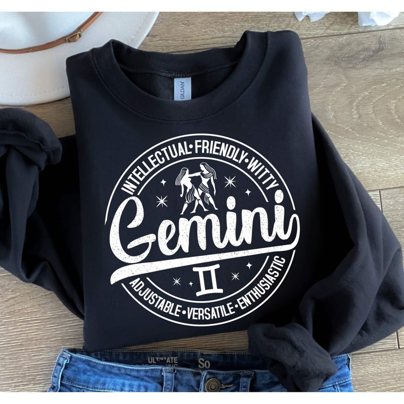May include: Black sweatshirt with a white circle graphic featuring the zodiac sign Gemini. The circle has the text "Intellectual-Friendly-Witty-Adjustable-Versatile-Enthusiastic" around the outside and "Gemini II" inside the circle.