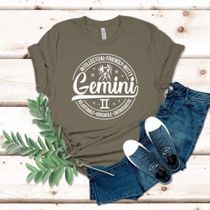 May include: A green t-shirt with a white circle graphic featuring the Gemini zodiac sign and the text "Gemini II Intellectual-Friendly-Witty Adjustable-Versatile-Enthusiastic".