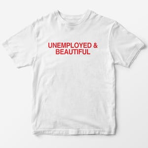 May include: A white t-shirt with the red text "UNEMPLOYED & BEAUTIFUL" printed across the front. The shirt is made of a soft, lightweight material and has short sleeves and a crew neck.