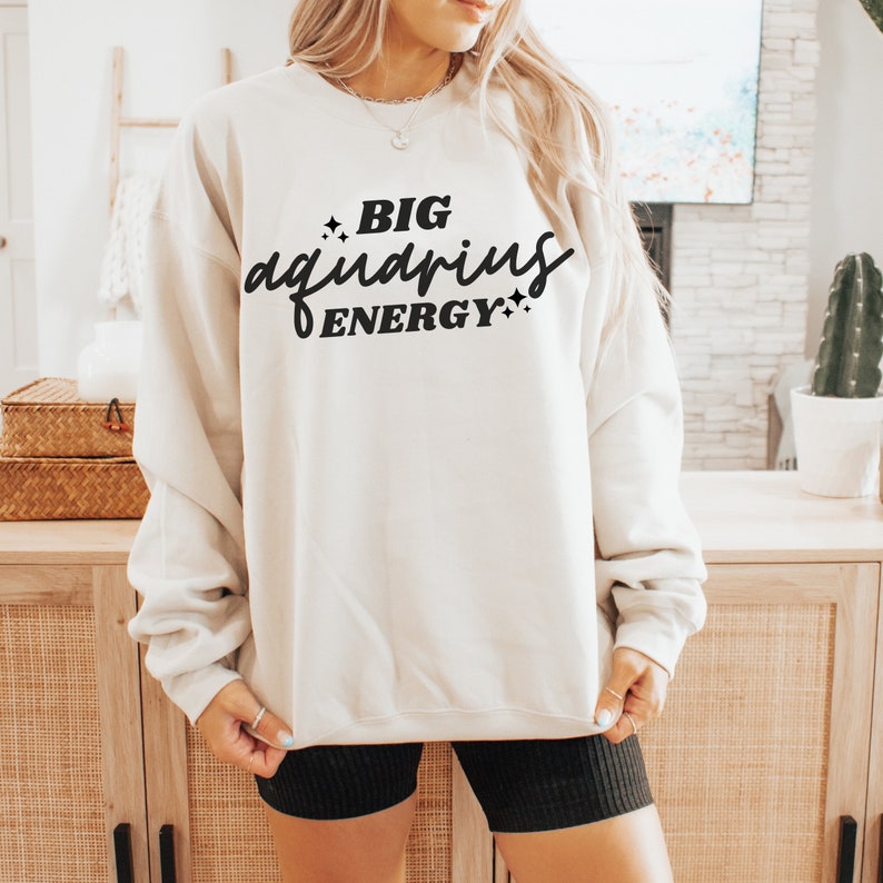 May include: A white sweatshirt with the text "BIG aquarius ENERGY" in black lettering.