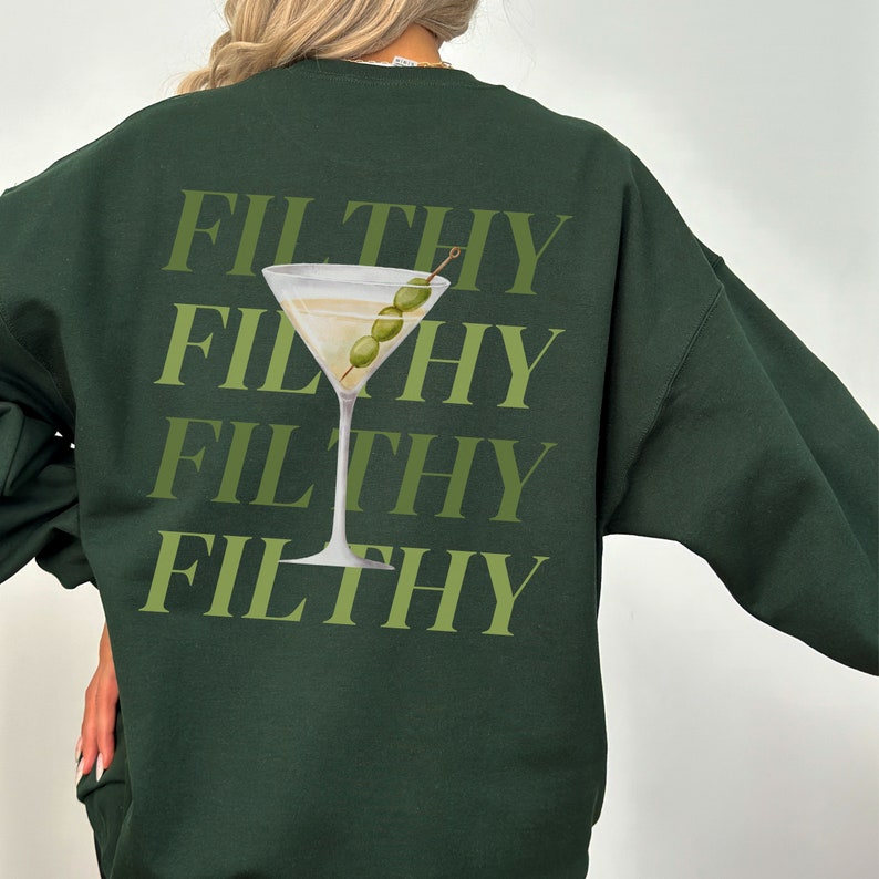 May include: Dark green sweatshirt featuring a graphic of a martini glass with olives and the word "FILTHY" repeated four times.