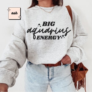 May include: A grey sweatshirt with the text "BIG aquarius ENERGY" printed in black.