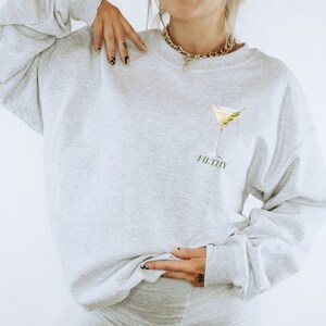 May include: A grey sweatshirt with a martini glass and olives graphic and the word "FILTHY" printed on the front.