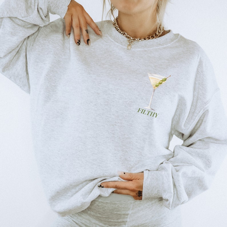 May include: A grey sweatshirt with a martini glass and olives graphic and the word "FILTHY" printed on the front.