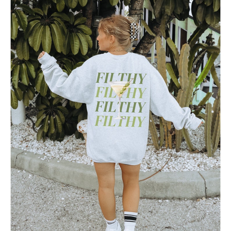 May include: A grey sweatshirt with the word "FILTHY" repeated four times in a stacked design. A green olive is in a martini glass graphic between the words.