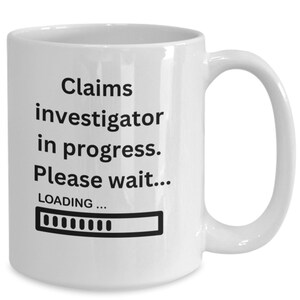 Puede incluir: Taza de café de cerámica blanca con texto negro que dice "Claims investigator in progress. Please wait... LOADING..." con una barra de progreso debajo.