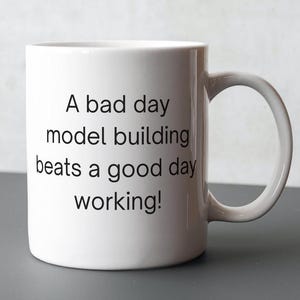 May include: White ceramic mug with black text that reads "A bad day model building beats a good day working!"