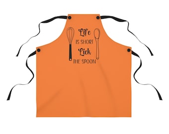 May include: Orange apron with black straps and a black print that says "Life is short, lick the spoon" with a whisk and spoon graphic.