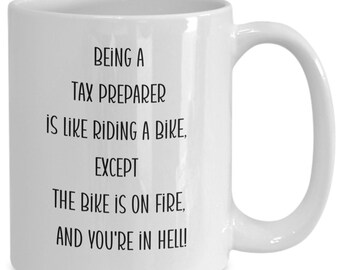 Puede incluir: Taza de café de cerámica blanca con texto negro que dice "Ser preparador de impuestos es como andar en bicicleta, excepto que la bicicleta está en llamas, ¡y estás en el infierno!"
