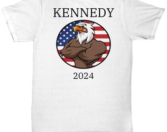 Könnte beinhalten: Weißes T-Shirt mit einem schwarz-roten amerikanischen Flaggen-Design, das einen Cartoon-Adler mit verschränkten Armen zeigt. Der Text "KENNEDY 2024" ist auf das Shirt gedruckt.