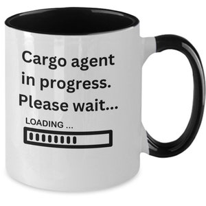 May include: White ceramic mug with a black interior, handle, and rim. The mug features the text "Cargo agent in progress. Please wait..." with a loading bar graphic, ideal for a cargo agent.