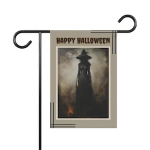 Puede incluir: Una bandera de jardín gris con el texto "Happy Halloween" impreso en naranja. La bandera presenta una ilustración en blanco y negro de una bruja de pie en un bosque brumoso.