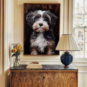 Pode incluir: Uma pintura emoldurada de um cão preto, branco e castanho com um fundo escuro. A pintura está pendurada numa parede acima de um armário de madeira com um tampo de mármore preto. Um candeeiro com um abajur de cor creme está sobre o armário.