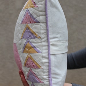 This shows the side of the pillow and the light purple piping that runs around the entire edge of the pillow.