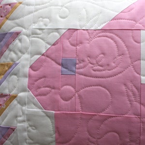This view shows the quilting pattern in more detail. Throughout the pillow there are carrots and rabbits stitched in white thread.