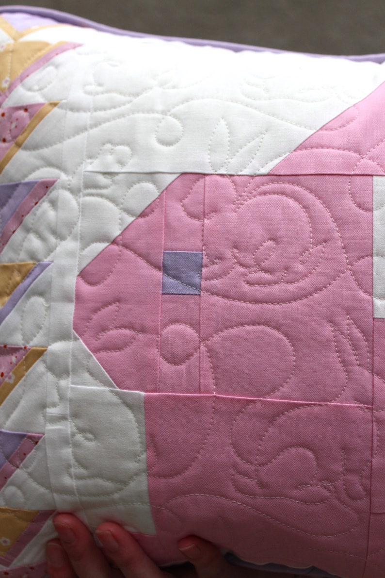 This view shows the quilting pattern in more detail. Throughout the pillow there are carrots and rabbits stitched in white thread.
