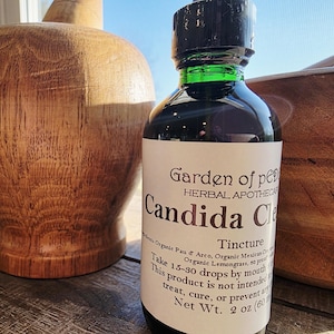 Peut inclure: Une bouteille en verre fonc&eacute; avec un bouchon noir et un anneau vert, &eacute;tiquet&eacute;e "Candida Cleanse" de Garden of Peace Herbal Apothecary. La bouteille contient un liquide fonc&eacute; et fait 60 ml.