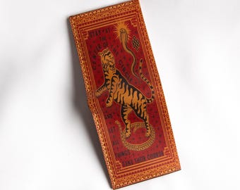 May include: A red leather wallet with a tiger and snake design. The wallet has a stitched border and the text "Stay at the center of the circle and let all things take their course".