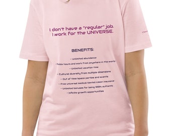 Op de afbeelding: Roze T-shirt met de tekst "Ik heb geen "gewone" baan. Ik werk voor het UNIVERSUM." en een lijst met voordelen, waaronder onbeperkte overvloed, flexibele werktijden, onbeperkte vakantie, culturele diversiteit, feestjes buiten tijd en ruimte, gratis universele medische/tandheelkundige/oogzorgverzekering, onbeperkte bonussen voor 100% authenticiteit en oneindige groeimogelijkheden.