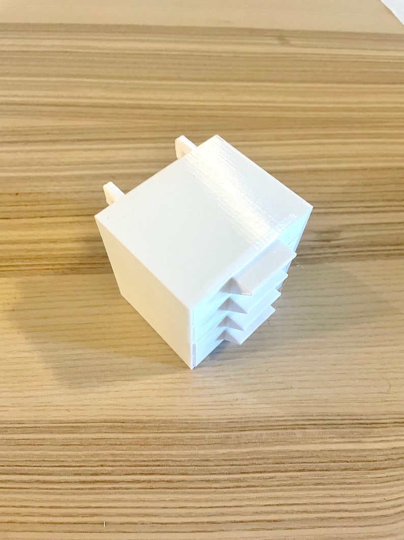 Puede incluir: Cubo de pl&aacute;stico blanco con una serie de peque&ntilde;as aberturas rectangulares inclinadas en un lado.