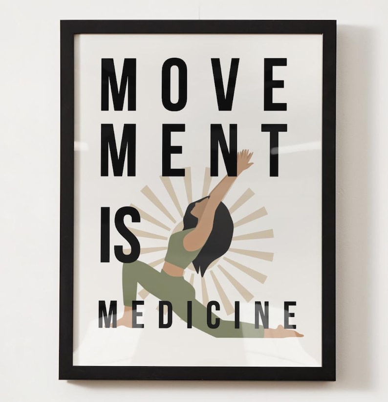 Op de afbeelding: Ingelijste kunstafdruk met de tekst "MOVEMENT IS MEDICINE" in zwarte letters. De afbeelding toont een vrouw in een yogahouding, gekleed in groene sportkleding, met een sunburst-ontwerp erachter. De lijst is zwart.