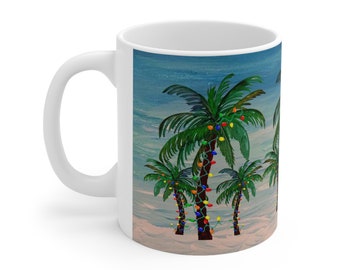 May include: White ceramic mug featuring a tropical scene with palm trees decorated with colorful Christmas lights. The background depicts a beach and sky. The mug has a curved handle and a glossy finish.