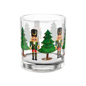 May include: A clear glass tumbler featuring a festive Christmas design. The tumbler showcases illustrations of toy soldier nutcrackers and green Christmas trees with colorful lights. The design is repeated around the glass.