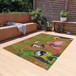 Puede incluir: Una alfombra rectangular con fondo de textura tejida color canela que presenta el texto verde brillante It's 5 O'clock Somewhere. El diseño incluye ilustraciones coloridas de un tucán, un flamenco rosa, un loro, una palmera y una copa de cóctel.