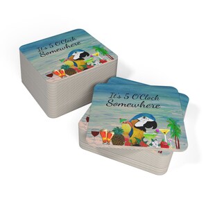 May include: Square coasters with a tropical theme. Each coaster features a parrot, cocktails, and the phrase "It's 5 O'Clock Somewhere" on a blue and white background. A stack of coasters is visible.