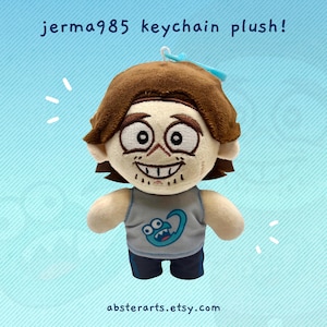 May include: A plush keychain featuring a cartoon character with brown hair and a gray tank top. The character has a wide grin and large eyes. The text "jerma985 keychain plush!" is above the plush, and the Etsy shop name is below.