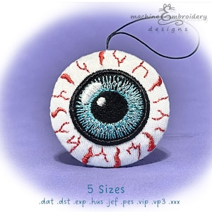 May include: Embroidered eye patch with a detailed blue iris, black pupil, and red veins on a white background. The patch has a black string attached. The text "machine embroidery designs" and "5 Sizes" are also visible.